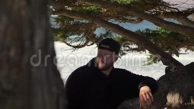 一张特写慢镜头的青年千禧坐在树上微笑着看着镜头。 日